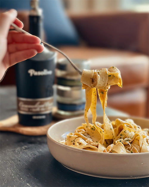 Pasolivo French Onion Pappardelle Pasta Recipe twirled on a fork next to Pasolivo Olive Oil and Spices