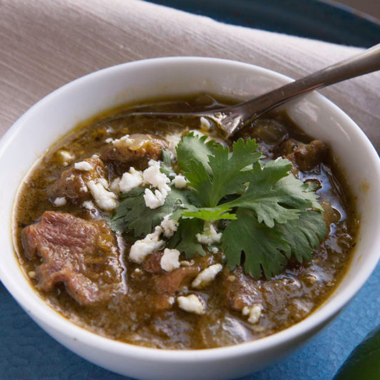 Pasolivo Green Chili Pork Recipe garnished with herbs 