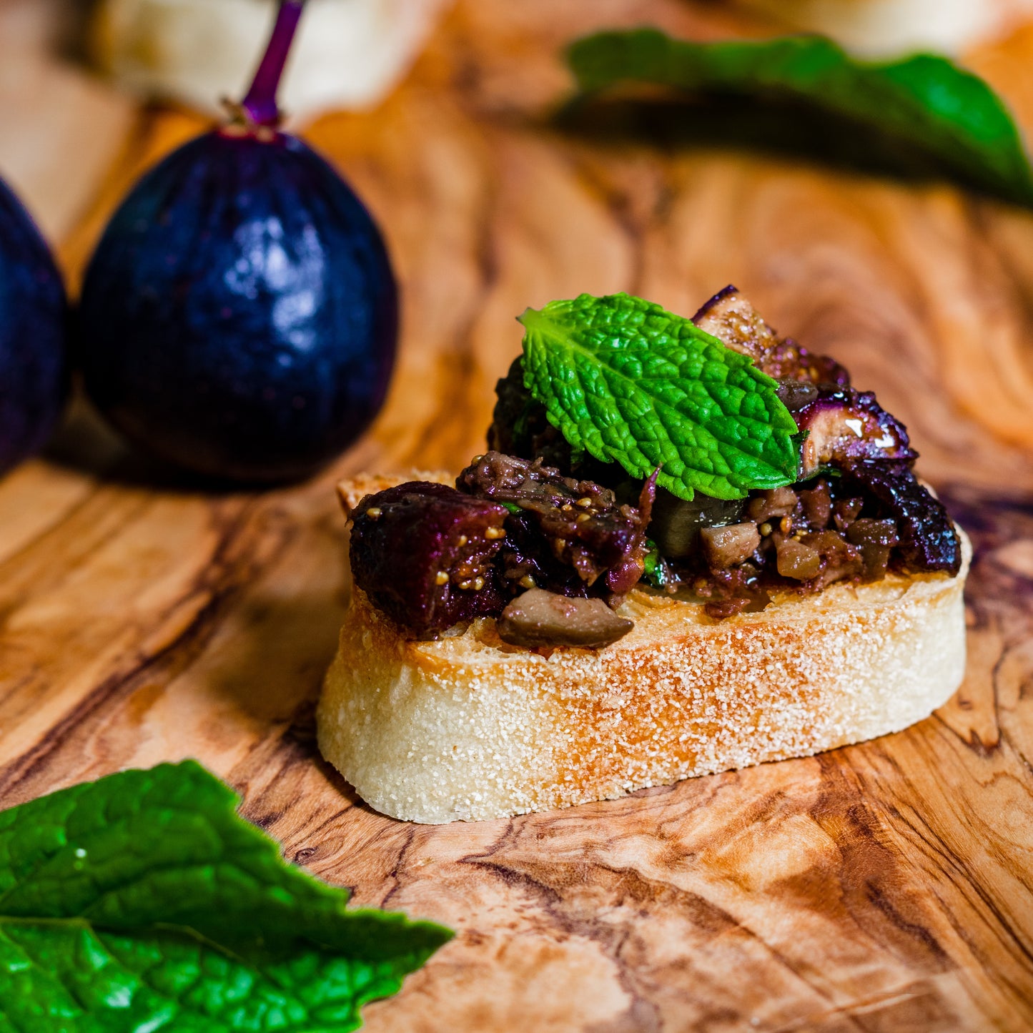 Pasolivo Tapenade & Figs Recipe next to fresh figs and garnished with mint