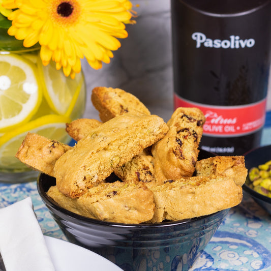 Pasolivo Cranberry Pistachio Biscotti Recipe in front of sunflowers and a Pasolivo Citrus Olive Oil Bottle