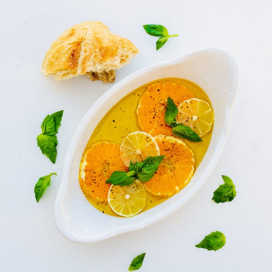 Pasolivo Oranges Recipe next to a piece of baguette and garnished with fresh herbs