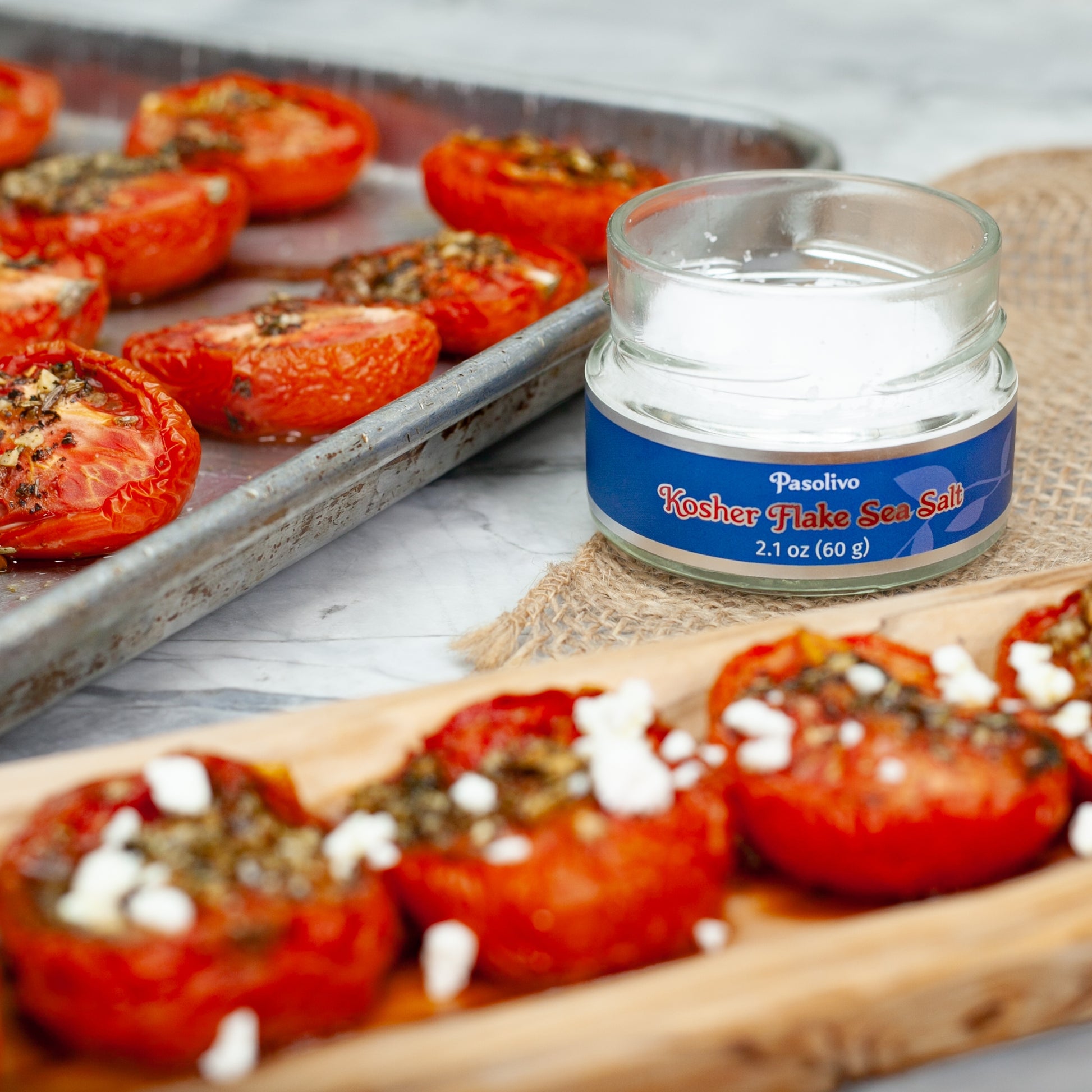 Oven Dried Tomatoes Recipe in a baking tray resting on countertop next to Pasolivo Kosher Flake Sea Salt