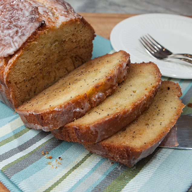 Pasolivo Poppyseed Tangerine Olive Oil Cake Recipe on a table next to an empty plate and forks