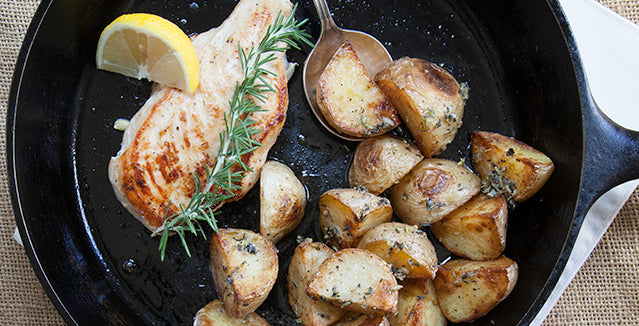 Pasolivo Yogurt & Citrus Olive Oil Chicken Recipe with a side of potatoes and garnished with rosemary and a lemon wedge 