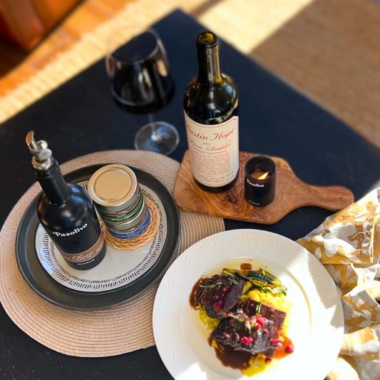 Pasolivo Cabernet Braised Short Rib Recipe on a table with a candle, wine, and Pasolivo Spices and Oils